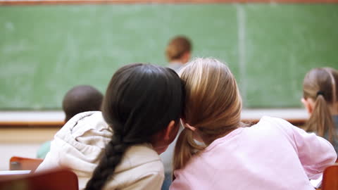 Children Whispering Secrets in Classroom