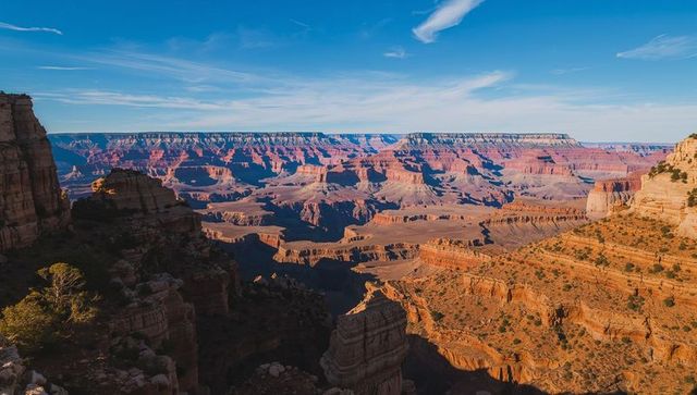 Sunlit grand canyon panorama with layered red sandstone cliffs, mesas and deep canyon