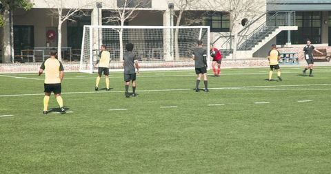 Soccer players strategizing near goal in competitive match