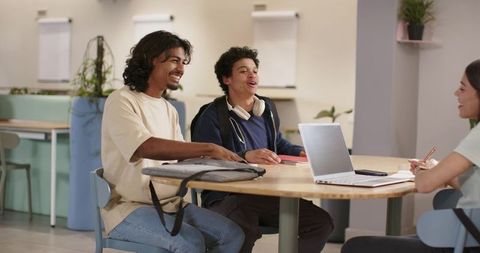 African American students collaborating at communal roundtable with laptop and notebooks