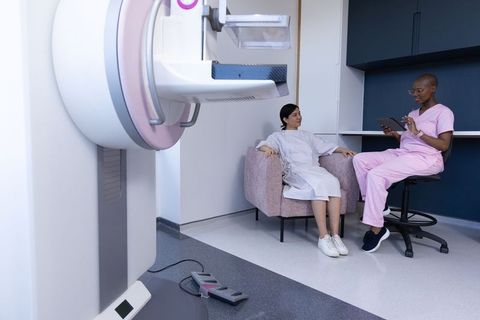 Diverse female patient consulting with imaging technologist before mammogram exam