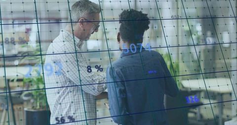 Collaborating over digital analytics dashboard with tablet in modern open office workspace