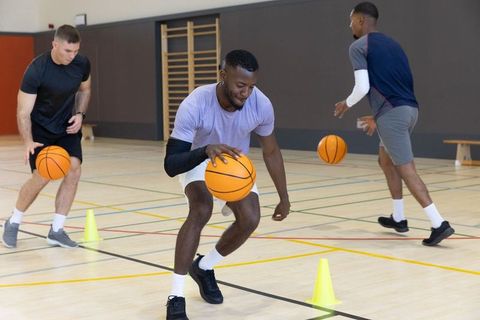 Men dribbling through cone drill on indoor court developing ball-handling skills