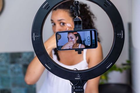 African american beauty creator applying undereye cream while filming with ring light