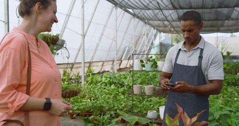 Woman Visiting Greenhouse Attendant with Smartphone