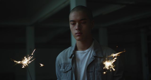 Young Man Holding Sparklers in Dark Room - Download Free Stock Images Pikwizard.com