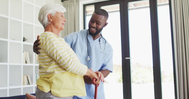 Image of happy african american male doctor supporting caucasian senior woman. seniors health and nursing home lifestyle concept.