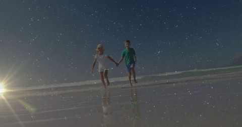 Siblings holding hands beyond starry horizon on beach