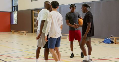 Young men planning basketball play in indoor gym holding ball teamwork practice