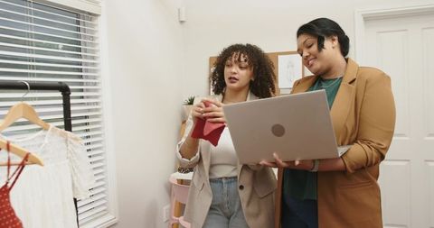 Fashion consultants collaborating on red fabric swatch in boutique styling session