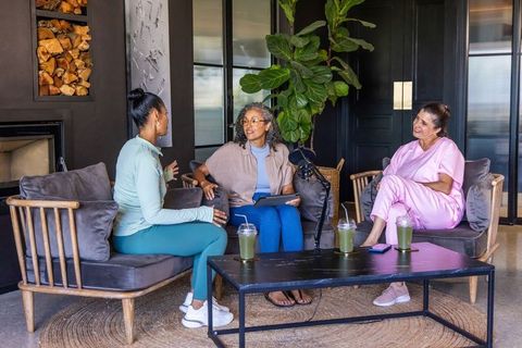 Diverse women chatting in cozy lounge recording casual wellness podcast conversation