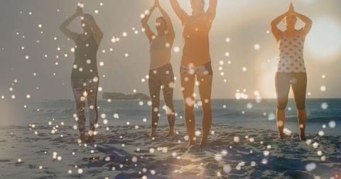Sunset yoga quartet practicing on beach with bokeh light, sun flare and barefoot meditation