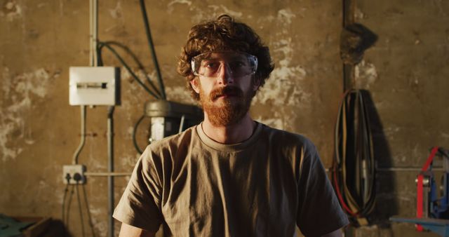 Portrait of caucasian male blacksmith wearing safety glasses in workshop. small business and craftsmanship at a blacksmiths forge.