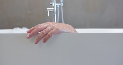 Relaxing Bath Hand with Soap Suds in Minimalist Bathroom