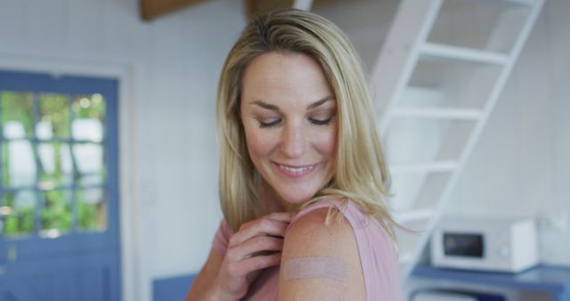 Smiling Woman Showing Arm with Bandage in Bright Home Interior - Download Free Stock Images Pikwizard.com