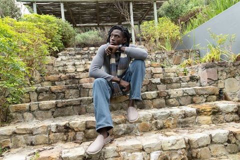 Contemplative african american man sitting on rustic stone steps in terraced garden pergola