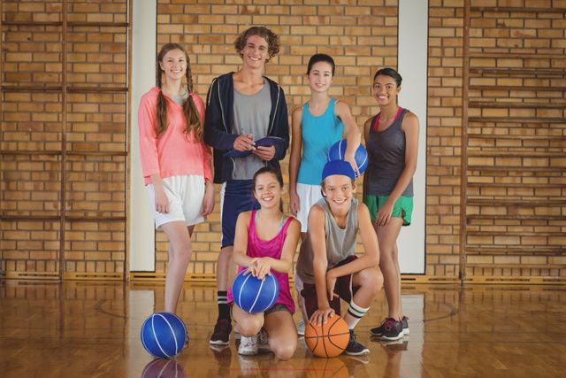 Portrait of high school kids with basketball standing together in basketball court