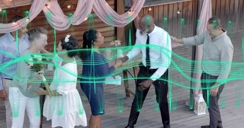 Outdoor wedding on wooden deck with guests shaking hands amid draped fabric and lanterns