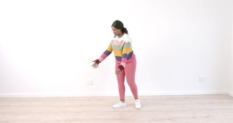 African american woman dancing energetically in vibrant sweater
