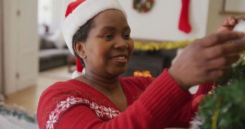 Senior Woman Joyfully Decorating Christmas Tree in Festive Living Room