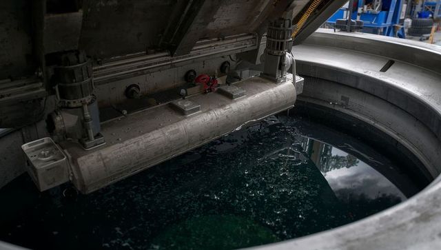 Horizontal scraper agitator stirring dark green process liquid in stainless steel tank
