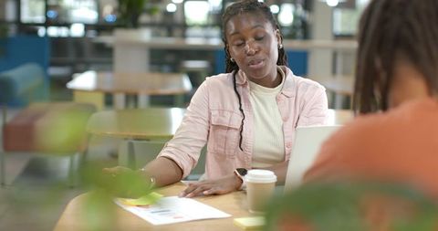 African American students collaborating at campus cafe with laptop and coffee
