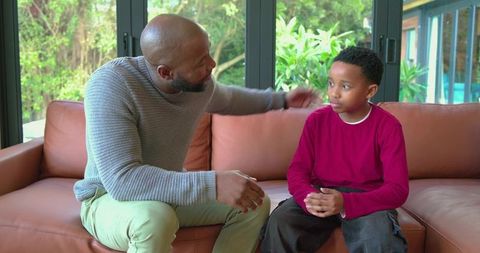 African american father comforting son on couch during gentle family conversation at home
