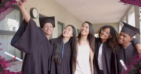 Graduates and mentor taking selfie in campus corridor celebrating college graduation