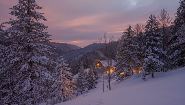 Glowing Alpine Cabin Nesting in Snowy Forest at Dusk with Warm Lights and Pink Sky