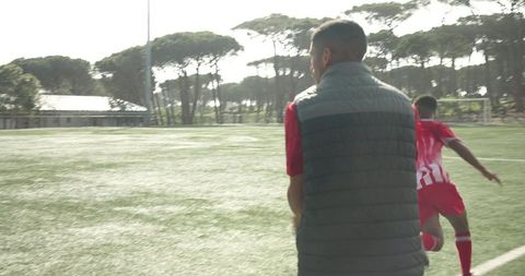 Youth soccer coach guiding players during outdoor training session