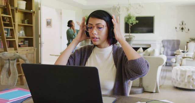 Focused woman using laptop with headphones in living room - Download Free Stock Images Pikwizard.com