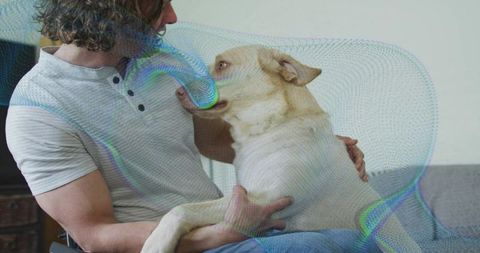 Man Cradling Light-Colored Dog in Cozy Living Room Setting