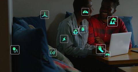 Couple researching home energy efficiency on laptop while smiling on sofa with green icons