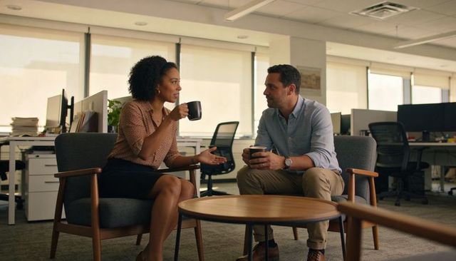 Coworkers Discussing Ideas in Office Lounge over Coffee Casual Business Conversation