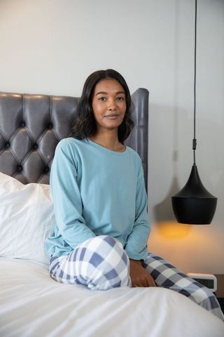 Woman Relaxing in Pajamas on Elegant Bed in Serene Bedroom