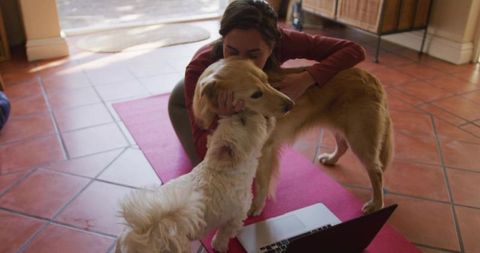 Woman Hugging Golden Retriever on Yoga Mat with Laptop at Home