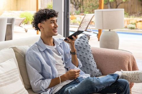 Young Man Using Voice Assistant on Smartphone in Cozy Home Setting