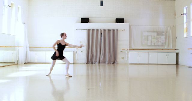 Ballerina practicing ballet moves in a bright, spacious dance studio with white walls and large mirrors. Ideal for use in articles, blog posts, and marketing materials about dance education, performing arts, and ballet training.