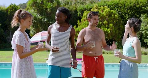 Diverse Friends Socializing Poolside with Drinks Near BBQ