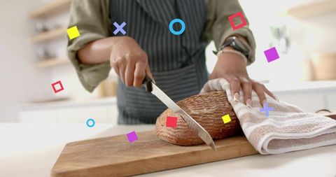 Woman slicing rustic artisan bread on wooden board in bright home kitchen