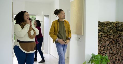 Diverse friends touring bright modern home entry admiring stacked firewood and greenery