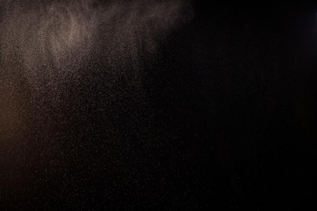 This image shows fine dust particles floating in a dark background, creating an abstract and atmospheric effect. It can be used for themes related to air quality, pollution, environmental issues, or as a texture for creative projects. Ideal for use in presentations, websites, or educational materials discussing air pollution or microscopic particles.