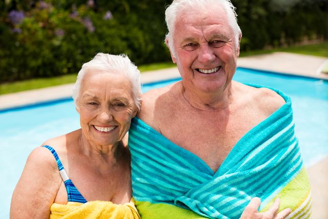 Senior couple wrapped in towel at poolside