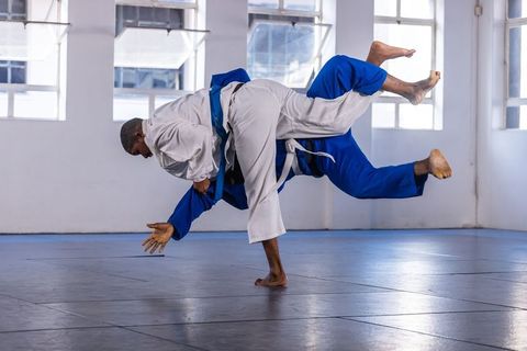 Athletic Men Training Judo Throw in Modern Gym