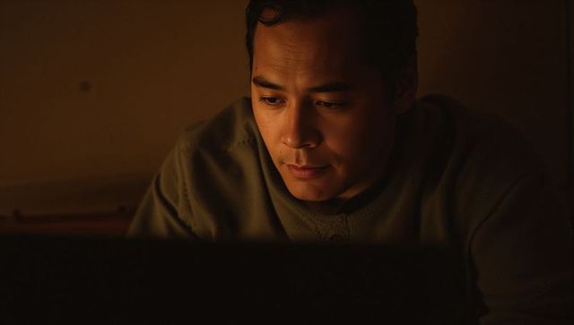 Working late on laptop with warm moody glow, man focusing at bedroom desk, intimate closeup