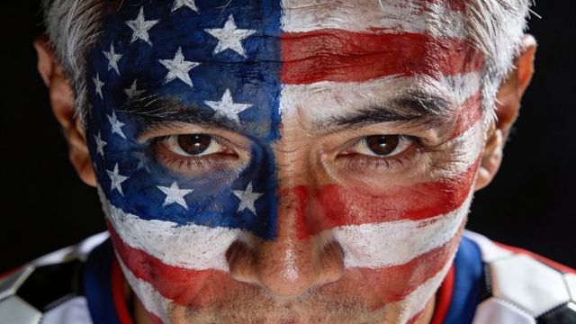 Intense male portrait with american flag face paint closeup, patriotic sports fan game day
