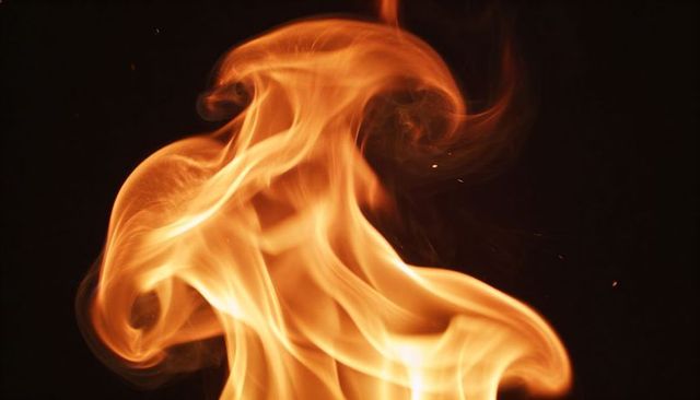 Swirling orange flame column dancing on black background for dramatic fire visuals