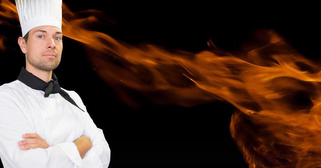 Digital composition of chef standing with arms crossed against fire on black background