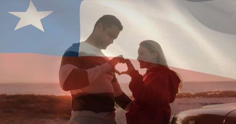 Romantic couple forming heart hands at beach sunset with chile flag double exposure