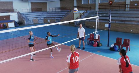 Teenage girls engaged in intense volleyball game in gym